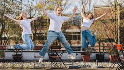 Drei junge Menschen springen in die Luft.