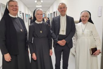 Drei Ordensschwestern und ein Bischof stehen gemeinsam in einem Krankenhausflur.
