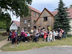 eine große Gruppe von Senioren sitzen erfreut vor dem Mühlencafé.