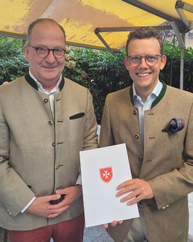 Patrick Tapp (links), Regionalleiter Hessen/Rheinland-Pfalz/Saarland, überreicht Ma-ximilian Graf von Plettenberg die Berufungsurkunde zum Diözesanleiter der Malteser im Bistum Limburg. (Foto: Malteser Limburg)