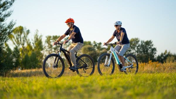 Es wird ein älteres Paar gezeigt, welches eine Tour mit dem E-Bike macht.