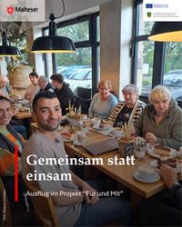 Viele Menschen sitzen am Tisch beim Bäcker und schauen lächelnd in die Kamera.
