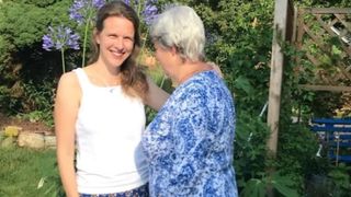 Eine Frau steht mit ihrer an Alzheimer erkrankten Mutter im Garten.