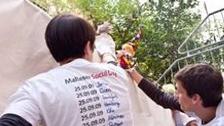 Zwei Jungen malen etwas auf ein Plakat. Sie tragen weiße T-Shirts mit der Aufschrift Social Day.