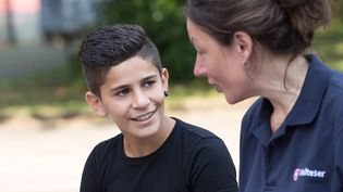 Eine junge Malteser Integrationslotsin unterhält sich mit einem Jungen.