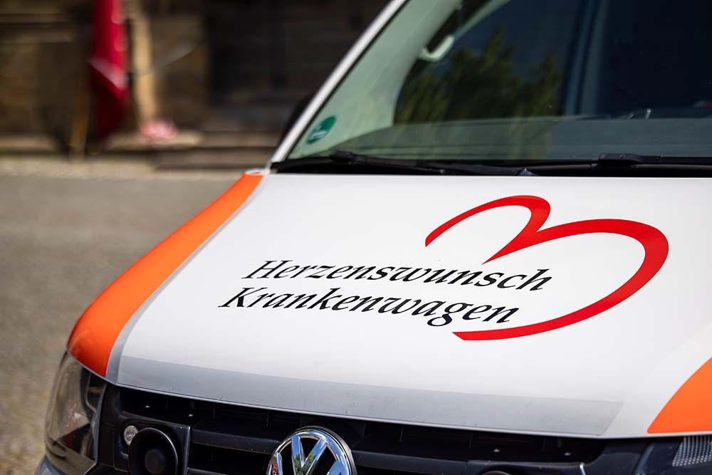 Auf der Motorhaube eines Rettungsfahrzeugs steht Herzenswunsch-Krankenwagen.