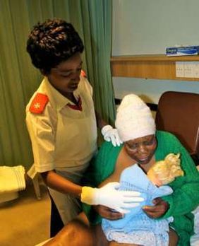 Caregiver tending to Thobile and her doll in the hospice