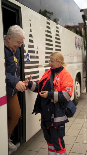 Eine Malteser Helferin begleitet den Ausstieg einer Pilgerin aus dem Bus bei der Ankunft in Kevelaer