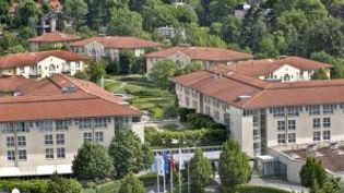Großzügige Hotelanlage mit mehreren Gebäuden, roten Ziegeldächern und grüner Parkanlage in ruhiger Umgebung.