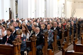 Viele Menschen sitzen in vollen Kirchenbänken