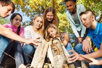 Jugend Menschen sitzen in einem Wald und blicken auf verschiedene Hölzer