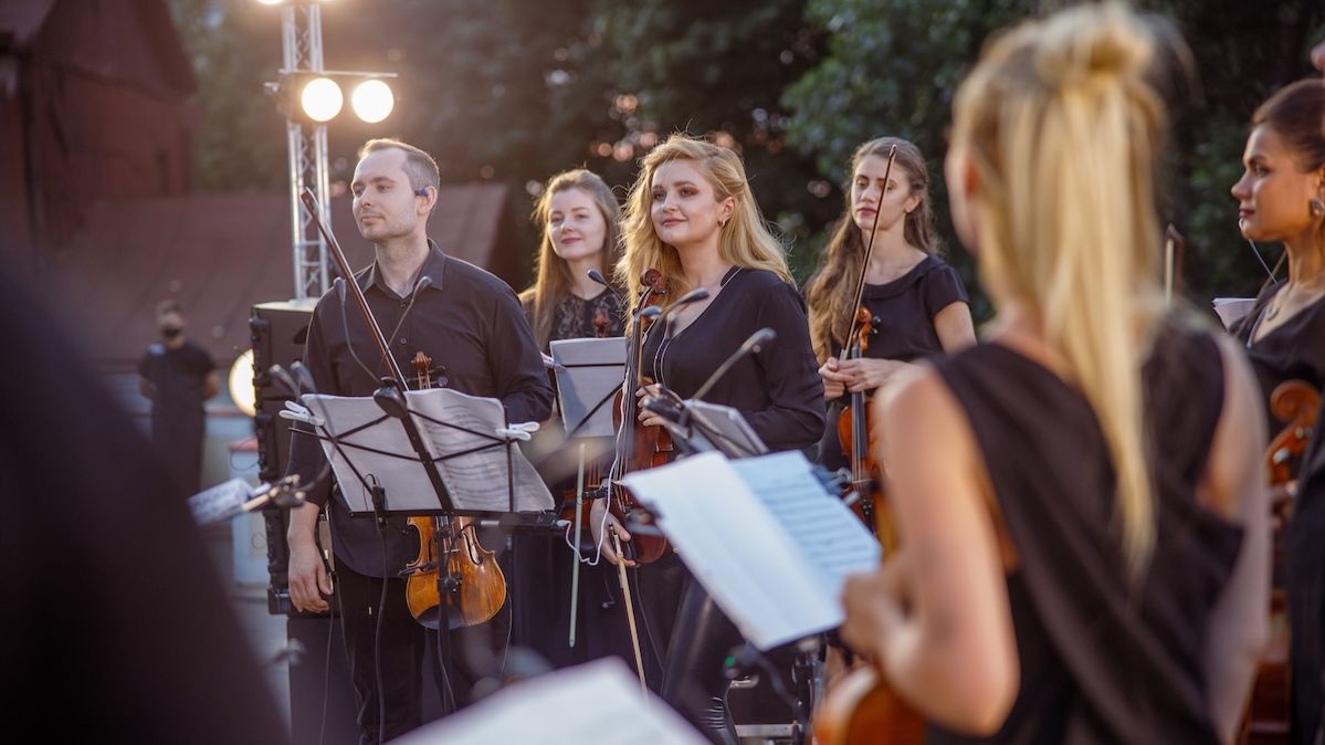 Musikerinnen und Musiker eines Orchesters bei einem abendlichen Auftritt im Freien 