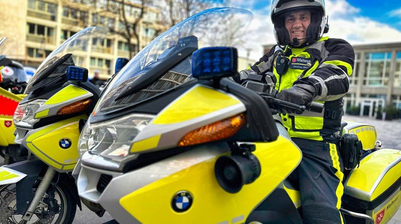 Mann in Motorradkluft und Helm sitzt auf einem gelben Motorrad.