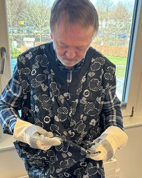 Ein Mann mit Handschuhen und einer Kittelschürze