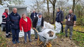 Ein Mann mit Schubkarre und Brennholz inmitten von anderen Helfern