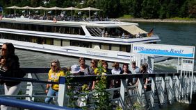 Eine Gruppe von Personen verlässt über einen Anleger ein Ausflugsschiff