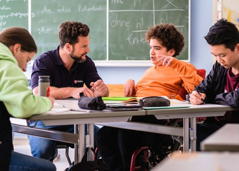 Ein Erwachsener an einem Tisch zusammen mit Schülern