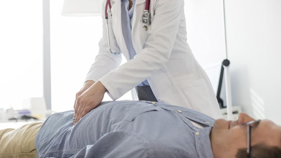 Mann wird von einer Ärztin abgetastet.