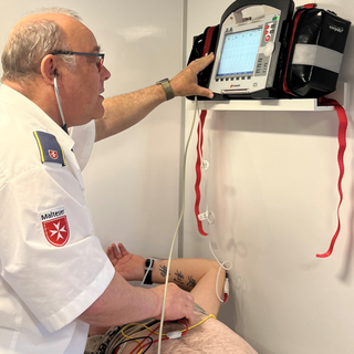 Arzt der einen Defibrillator ausliest von einem Mann.