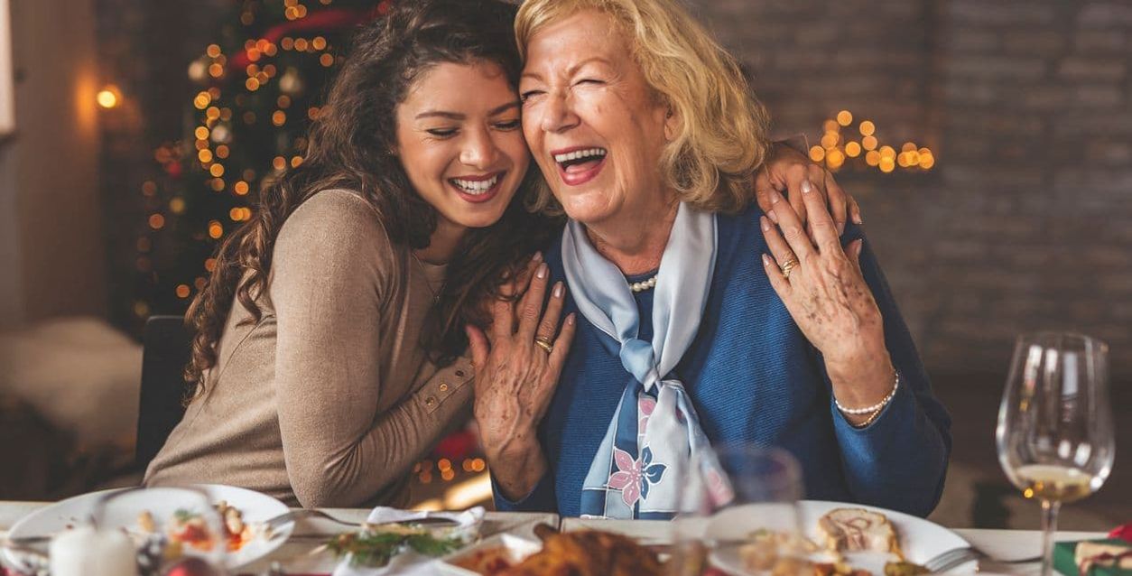 Zwei Frauen lachen zusammen während des Weihnachtsessens.