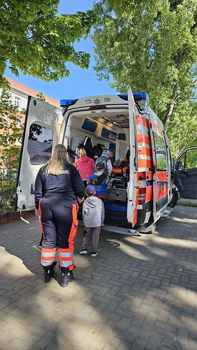 Kinder eines Kindergartens schauen sich einen Rettungswagen an