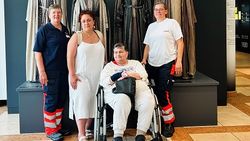 Eine Frau im Rollstuhl und drei Begleiterinnen vor Figuren, die Kostüme der Oberammergauer Passionsspiele tragen.