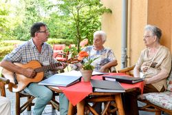 Sozialer Dienst spielt mit der Gitarre Lieder für die Bewohner 