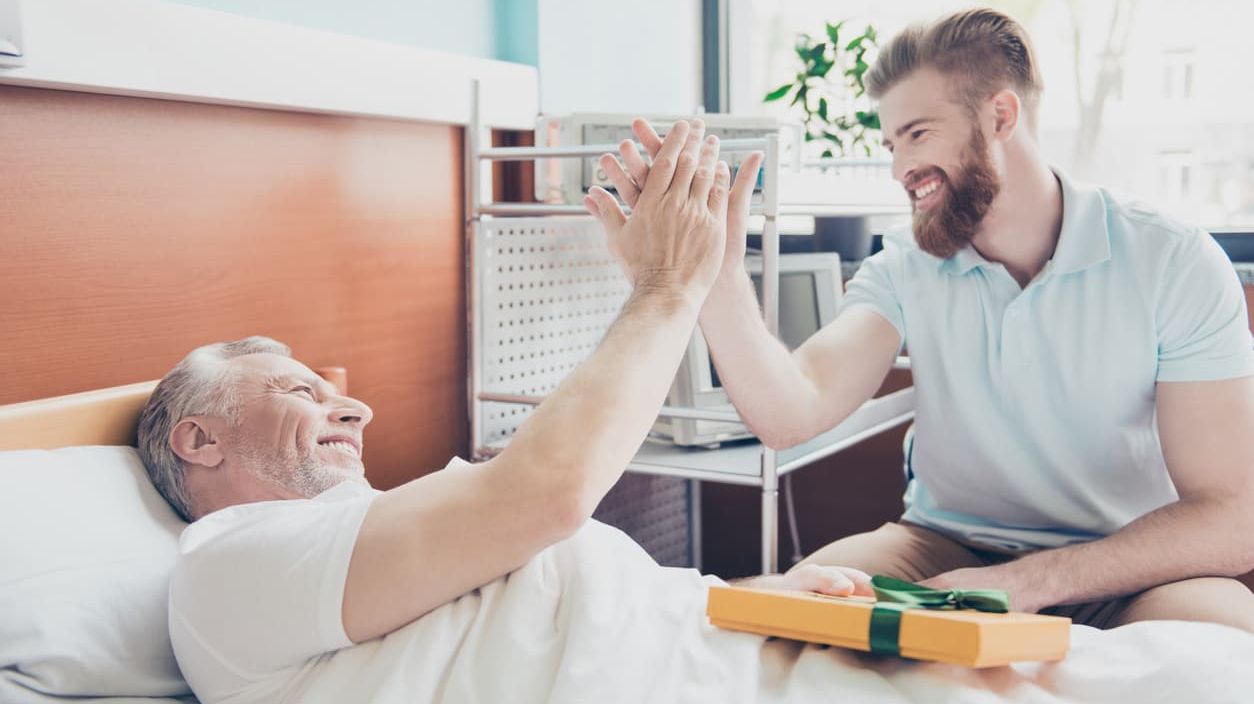 Junger Mann gibt Pflegebedürftigem ein High Five