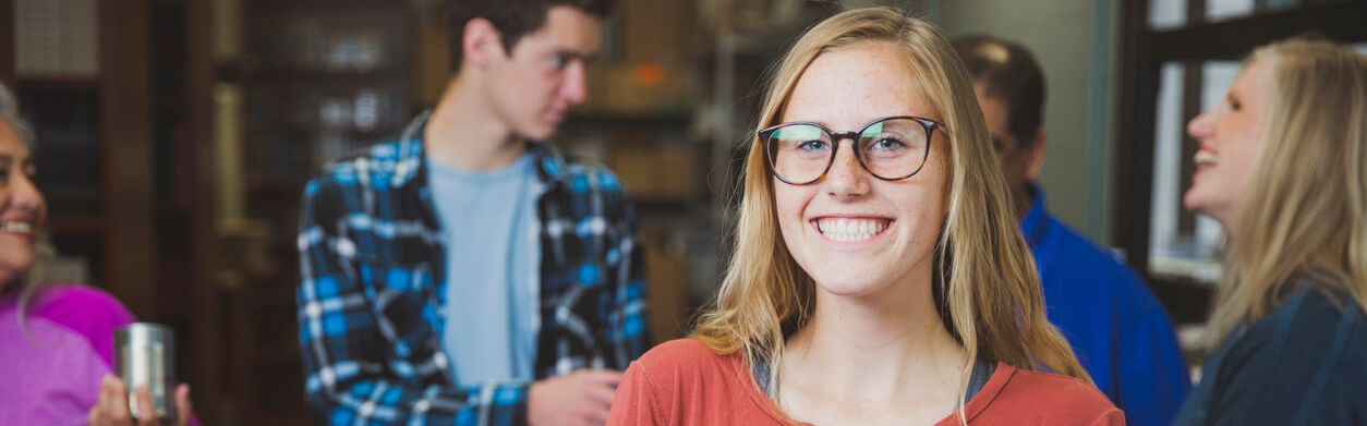 Portrait einer jungen Frau, die vor anderen Menschen steht