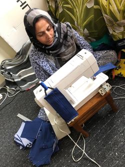 Geflüchtete Frau näht an einer Nähmaschine im Projekt der Malteser Flüchtlingshilfe.