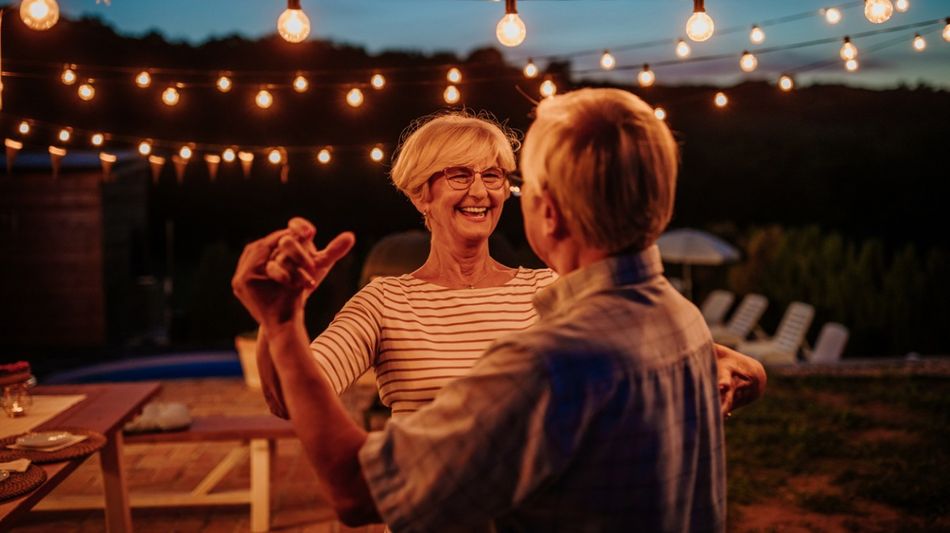 Ein Seniorenpaar tanzt im Freien unter Lampenlicht