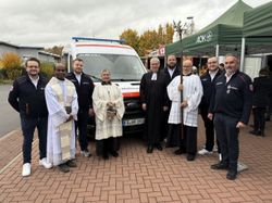 Vor dem neuen Katastrophenschutzfahrzeug der Malteser stehen acht Personen nebeneinander. Sie freuen sich über die Segnung des Fahrzeugs. Von links nach rechts: Christoph Wagner (Wachleiter Jesberg/Gilserberg), Pater Simon (Herz-Jesu-Gemeinde Fritzlar), Constantin Mühr (Bereichsleiter Malteser Rettungsdienst Nord), Messdienerin Angelika Lippert, Pfarrer Gunnar Hartmann (evangelische Kirchengemeinde Gudensberg), Messdiener Wolfgang Lippert, Felix Siegel (Wachleiter Gudensberg) und Markus Schips (Geschäftsführer Malteser Rettungsdienst Hessen).