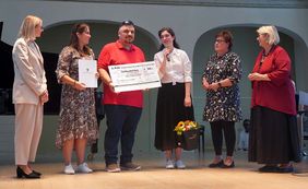 Eine Gruppe von Menschen hält einen Spendenscheck über 500 Euro. Damit wurde das Projekt "Dein Sozius" ausgezeichnet.
