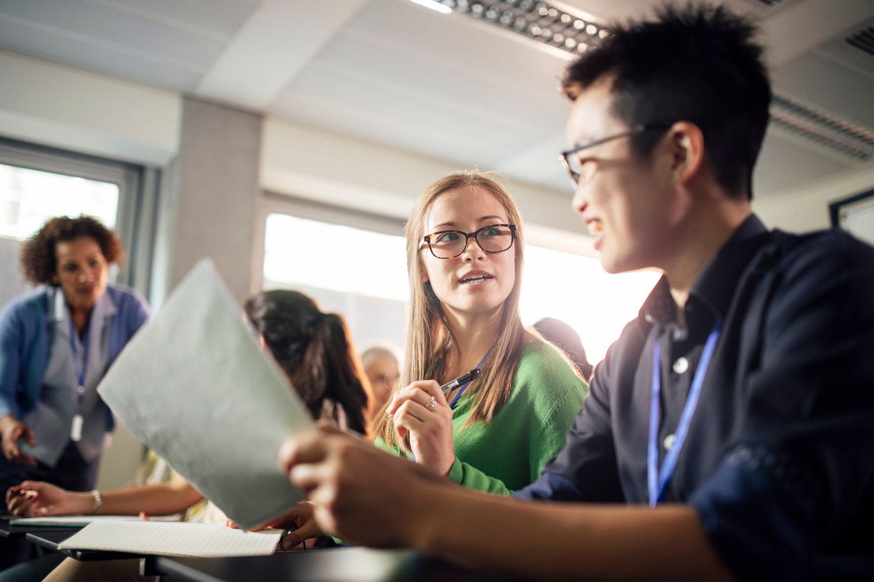 Junge Menschen in einem Klassenraum diskutieren miteinander.
