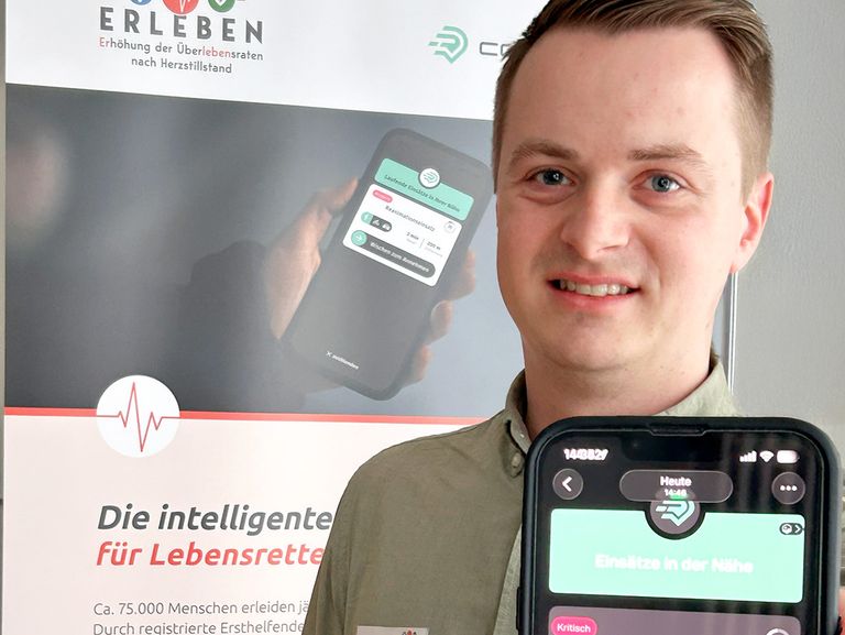 Ein Mann hält ein Handy mit der Ersthelfer-App in die Kamera.