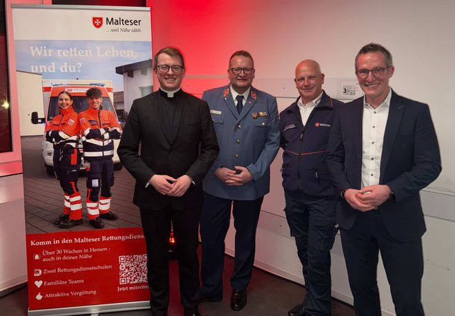 Lucas Weiss, Boris Falkenberg, Claus Kemp und Carsten Braun stehen vor einer Wand neben einem Banner auf dem Neujahrsempfang der Malteser