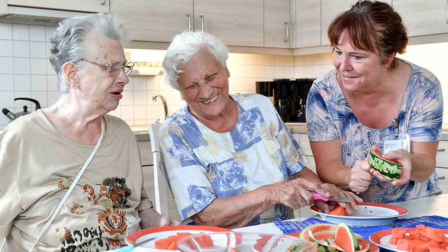 Bewohner und Pfleger essen gemeinsam Wassermelone 