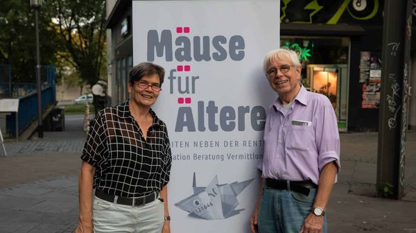 Seniorenpaar wirbt für das Straßenplakat: Mäuse für Ältere.