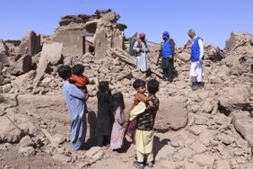 Erdbeben in Afghanistan. Menschen stehen auf dem Schutt zerstörter Häuser.