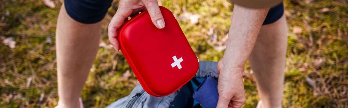 Eine Frau verstaut einen Erste-Hilfe-Kasten in einem Wanderrucksack