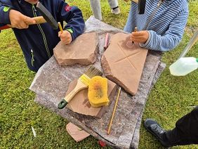 Kinderhände und die gemeißelten Sandsteinplatten in Nahaufnahme.
