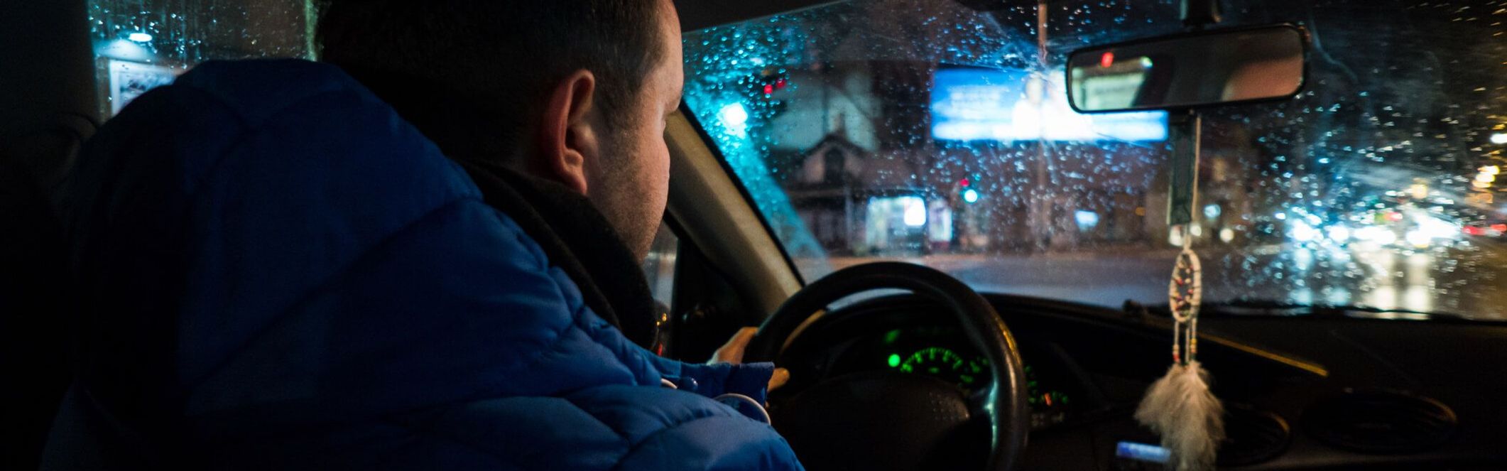 Junger Mann sitzt in Bus und fährt nachts.