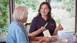 Junge und ältere Frau an einem Tisch mit Briefen