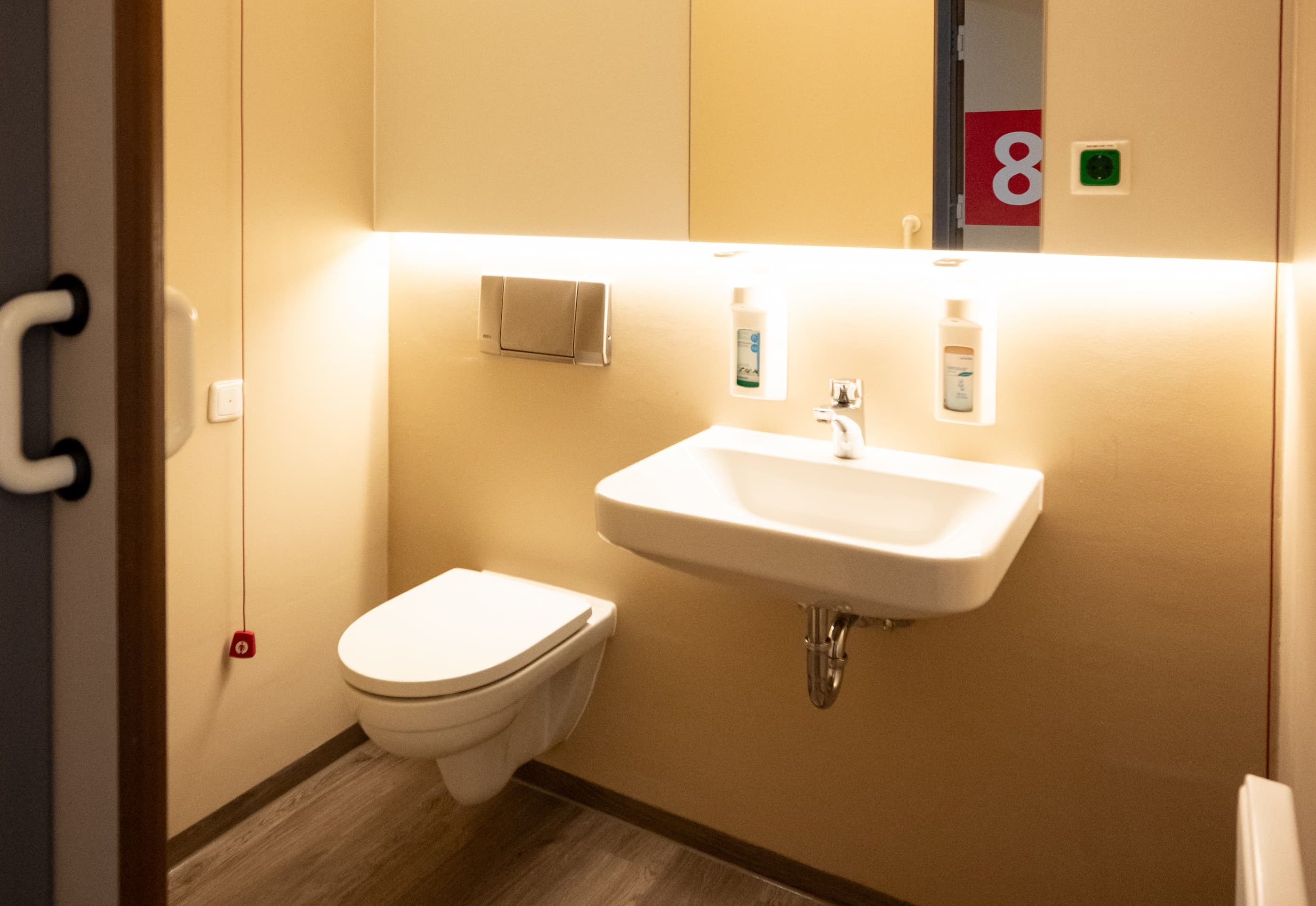 Helles, modernes Badezimmer mit Waschbecken, Toilette und einem großen Spiegel.