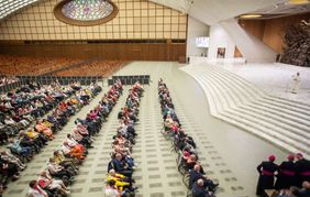 Papst Leo XIV. steht in einer Halle und spricht von einem Podest zu den Pilgern.