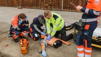 Drei jungen Menschen trainieren unter Beobachtung an einer Übungspuppe die Reanimation