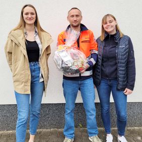 Zwei Frauen bedanken sich mit einem Präsentkorb bei einem Ausbilder des Lehrgangs für Rettungssanitäter