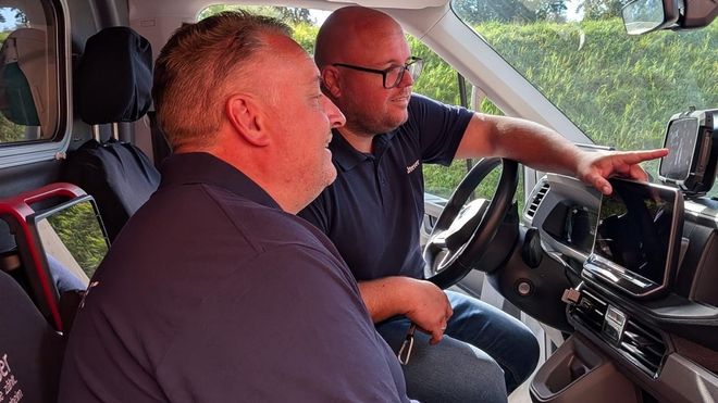Zwei Männer sitzen gemeinsam in eine Rettungswagen und schauen das eingebaute Einsatztablet an.