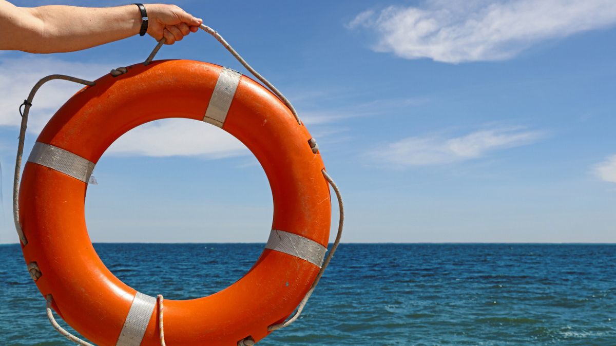 Rettungsring an ausgestreckter Hand über dem Meer