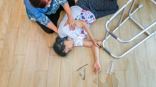 Ältere Frau versucht, eine am Boden liegende Frau in eine stabile Seitenlage zu bringen.